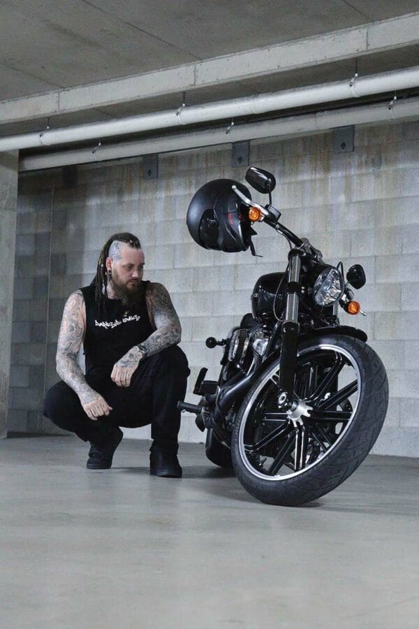 Male wearing a DSK Singlet crouching next to a motorcycle