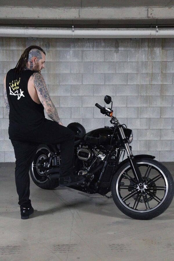 Male wearing a DSK Singlet while leaning against a motorcycle