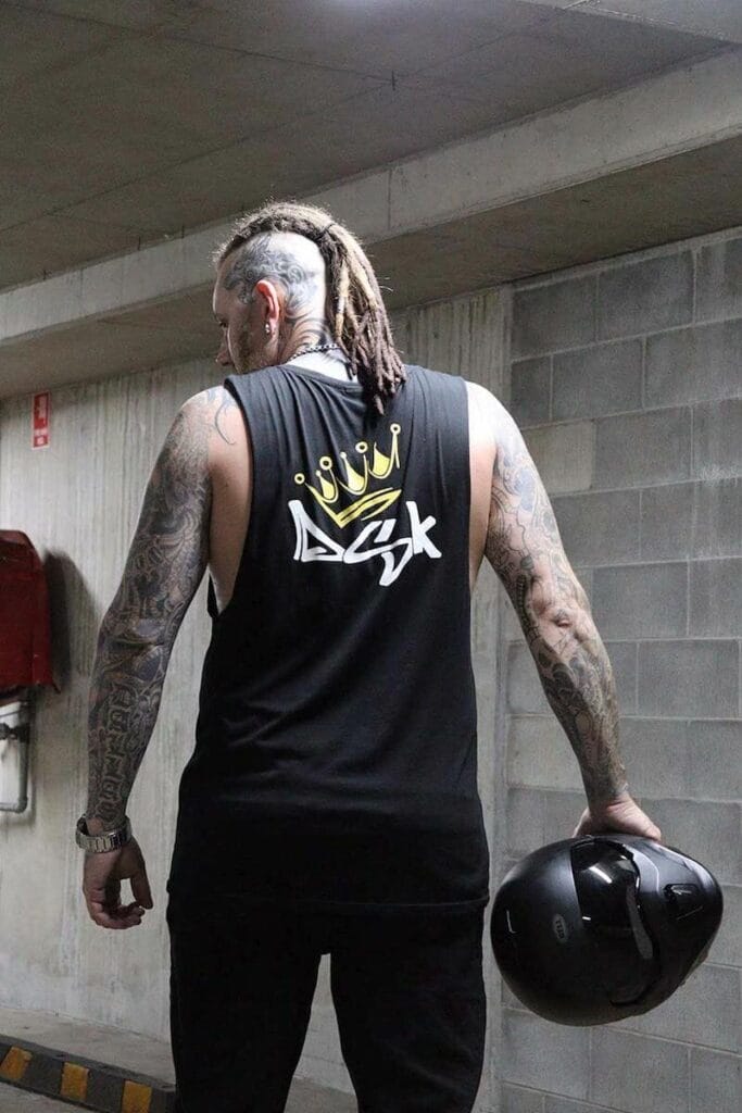 Back view of a male wearing a DSK Singlet while holding a motorcycle helmet