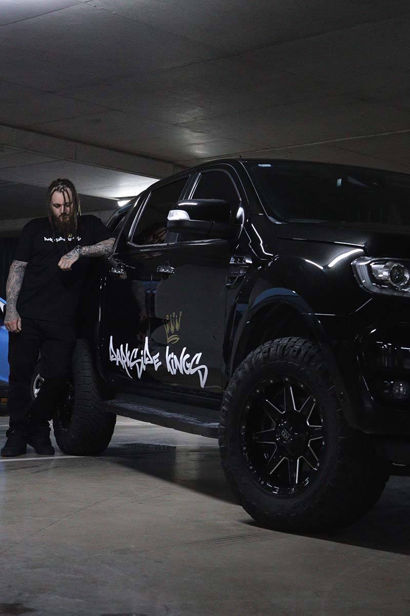 Male wearing a DSK T-shirt leaning against a Ford Ranger