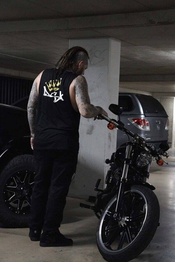 Back view of a male wearing a DSK Singlet standing next to motorcycle