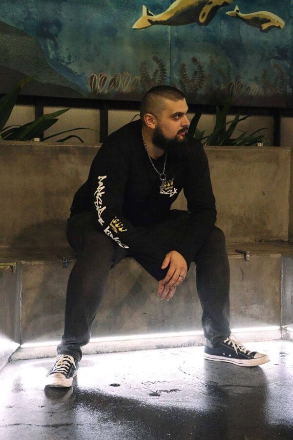 Male wearing a long sleeve DSK shirt sitting on concrete bench