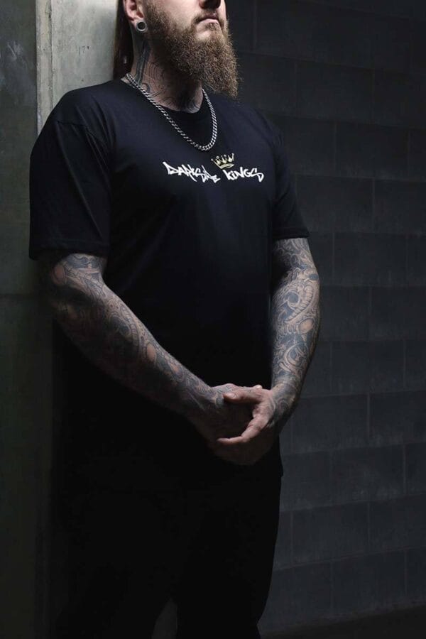 Male wearing a DSK T-shirt standing in front of a concrete wall