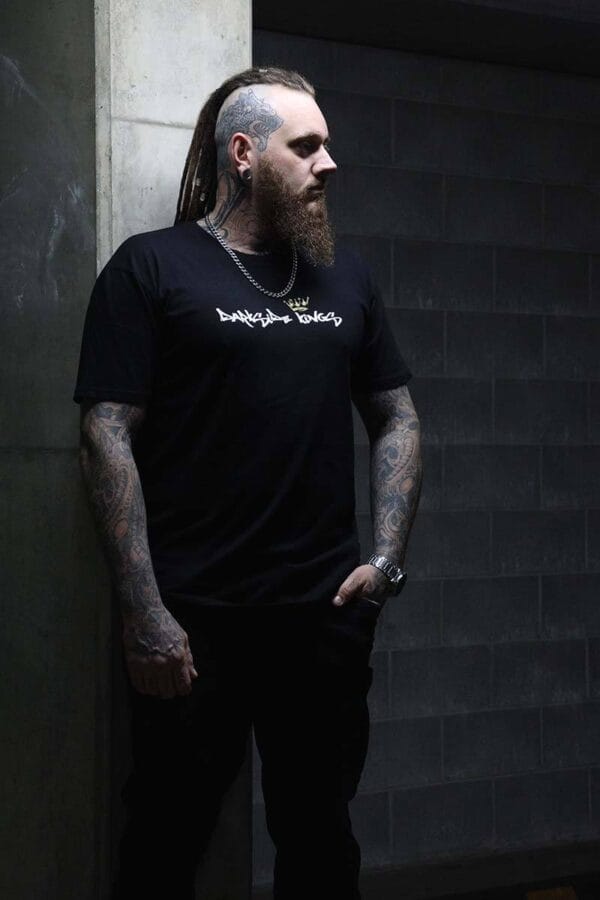 Male wearing a DSK T-shirt standing in front of a concrete wall