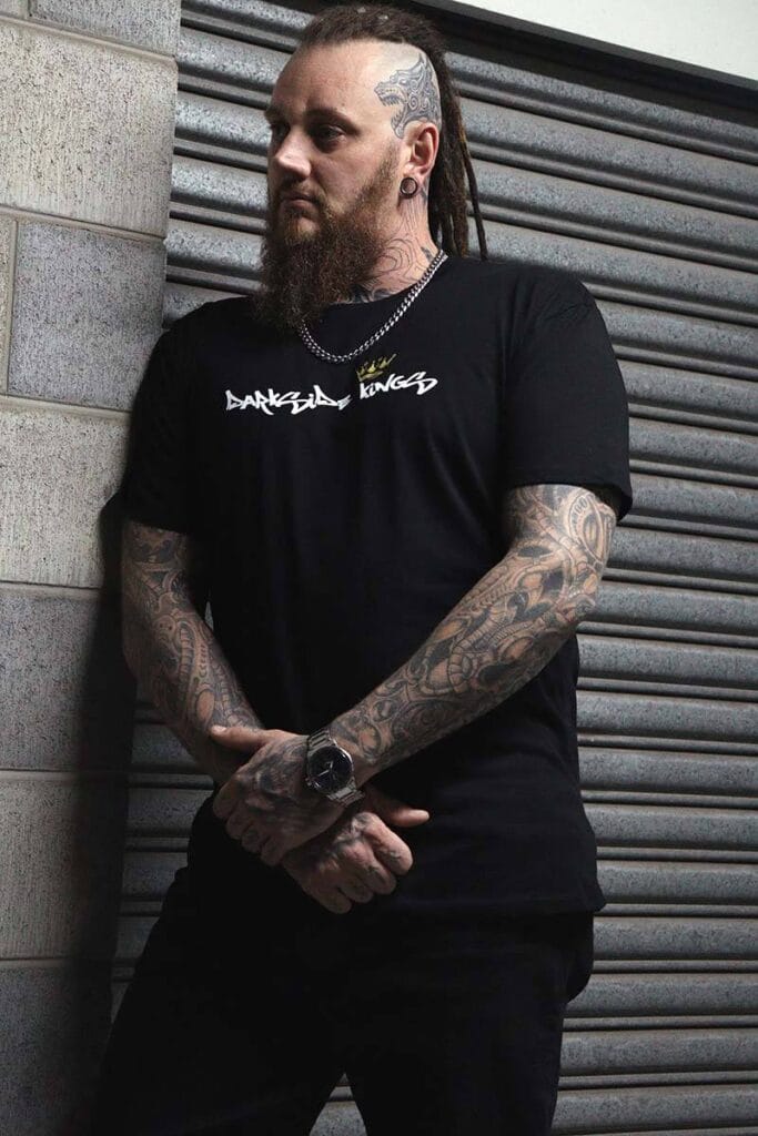 Male wearing a DSK T-shirt leaning against a concrete wall