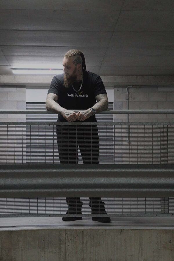 Male wearing a DSK T-shirt leaning over a railing