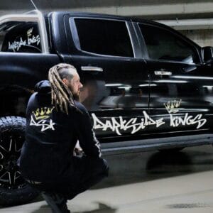 Male wearing a DSK Hoodie crouching in front of a black Ford Ranger with a large DSK sticker across the doors