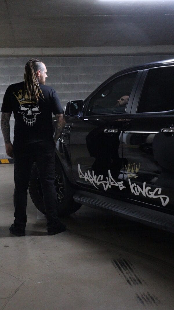 Male wearing a DSK Limited Edition t-shirt standing next to a Ford Ranger