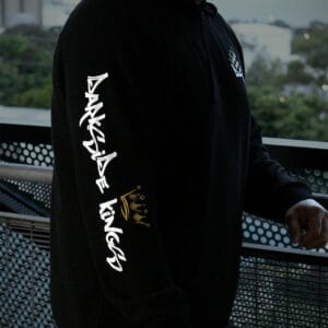Male leaning over a rail wearing a black hoodie with a Darkside Kings logo printed down the sleeve