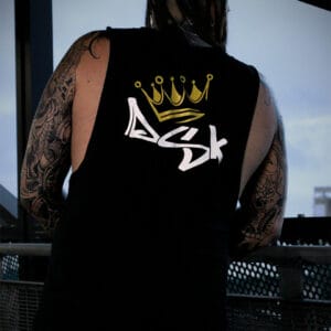 Male leaning over a rail wearing a black DSK logo tank top singlet