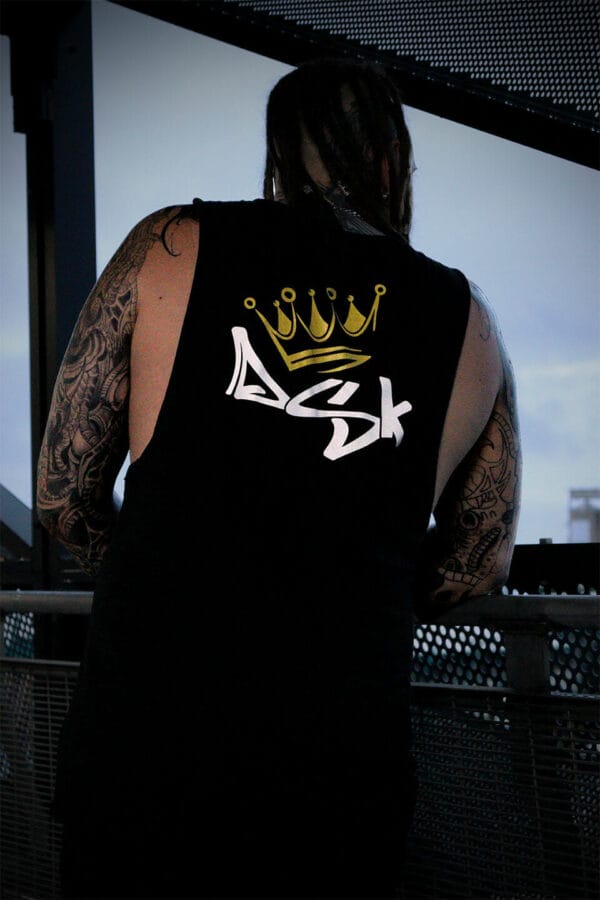 Male leaning over a rail wearing a black DSK logo tank top singlet